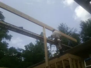 Carpenter setting a ridge beam over a new addition frame — Ice Dam Removal by Roofing Brothers in Clemmons
