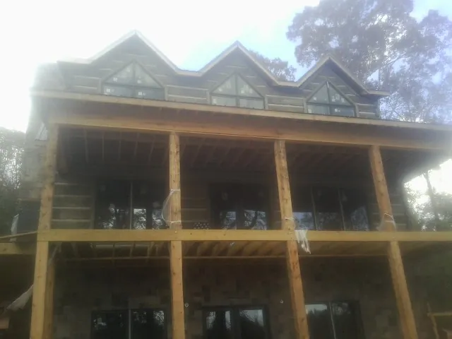 Dormers and porch framing on a large log home under construction — Roof Coating work by our crew in Clemmons