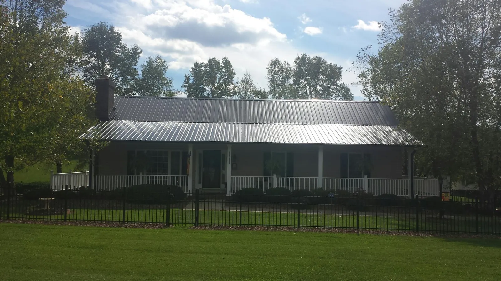 Gray metal roof on a brick ranch with a full width front porch — Gutter Guard Installation work by our crew in Clemmons